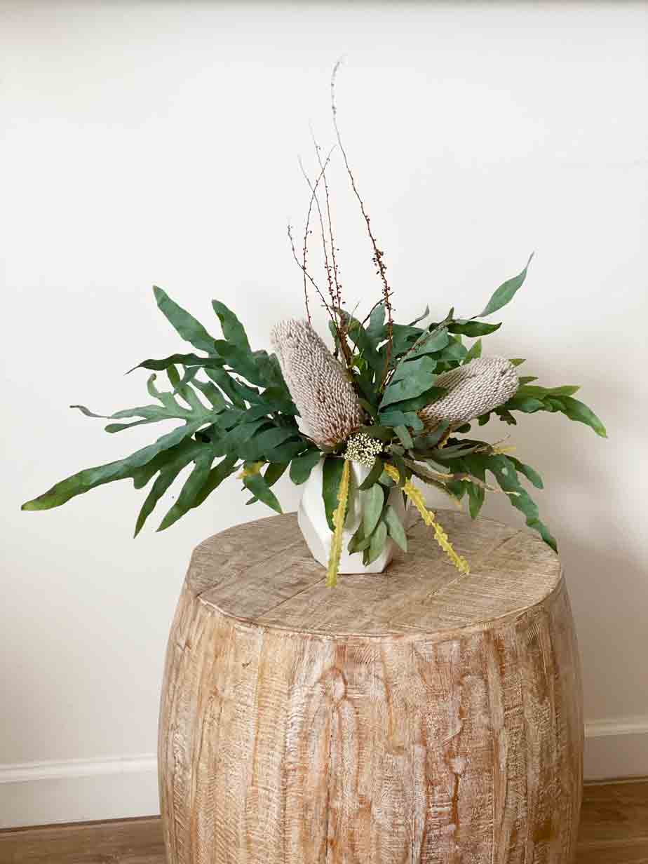Floral and foliage arrangement on a natural wood pedestal